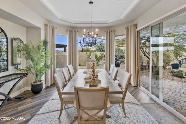 dining area featuring a raised ceiling, an inviting chandelier, and hardwood / wood-style flooring