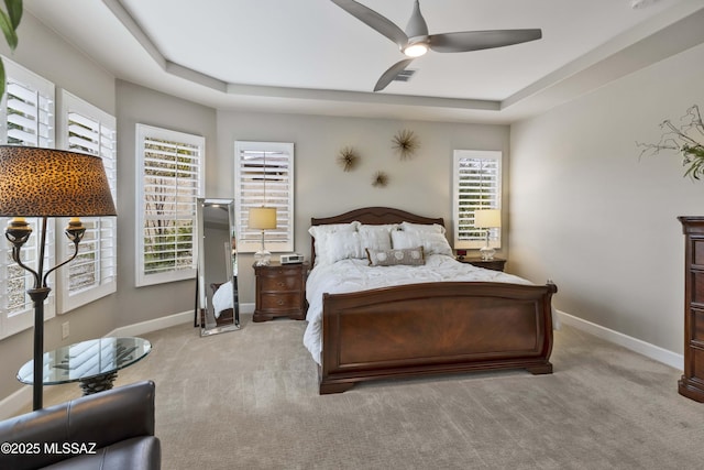 bedroom featuring light carpet, a raised ceiling, and ceiling fan