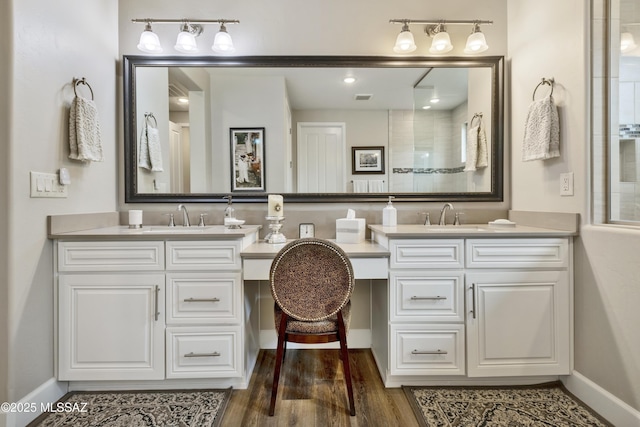 bathroom with hardwood / wood-style floors, vanity, and a tile shower