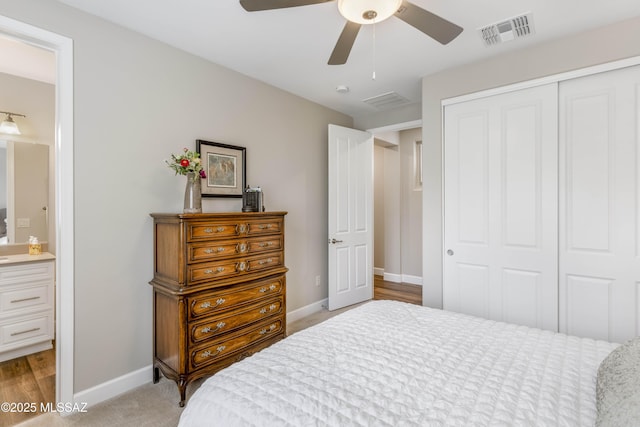 bedroom with ceiling fan, light colored carpet, connected bathroom, and a closet