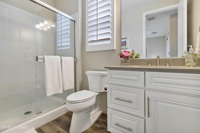 bathroom with wood-type flooring, vanity, toilet, and walk in shower