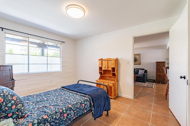 bedroom featuring brick wall and light tile patterned flooring