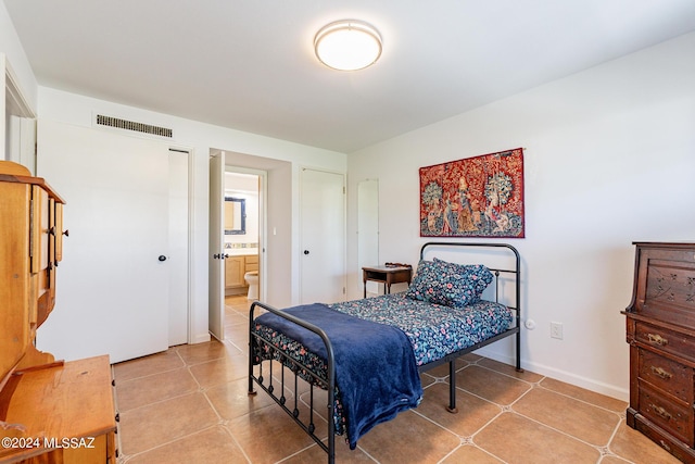 bedroom with baseboards, ensuite bathroom, visible vents, and tile patterned floors