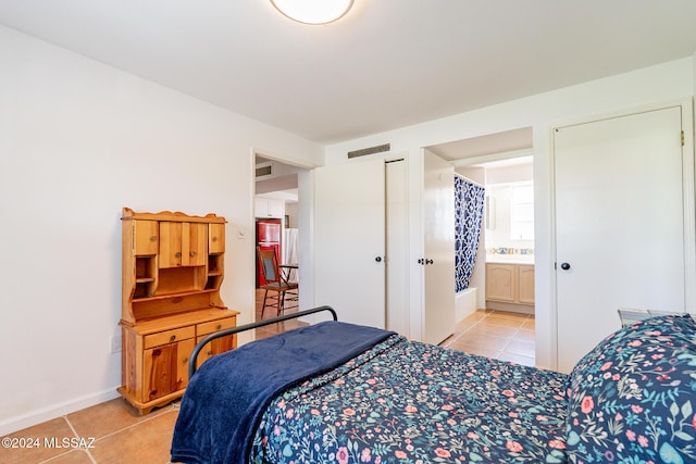 bedroom featuring visible vents, connected bathroom, baseboards, and light tile patterned floors