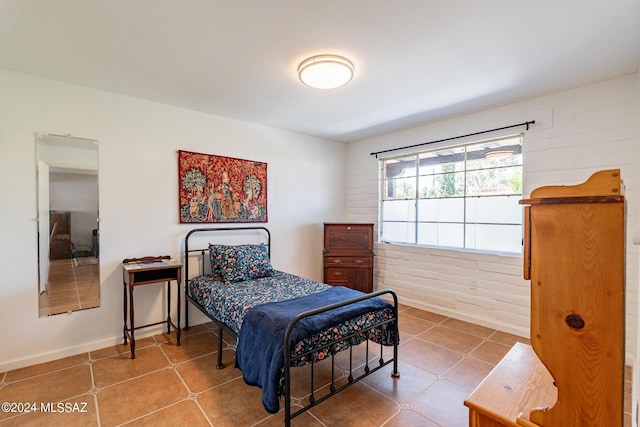 tiled bedroom featuring brick wall