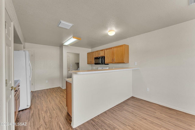 kitchen featuring kitchen peninsula, a textured ceiling, light hardwood / wood-style floors, and white fridge