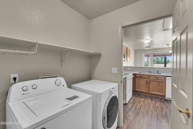 clothes washing area with sink, a textured ceiling, dark hardwood / wood-style flooring, and washing machine and clothes dryer