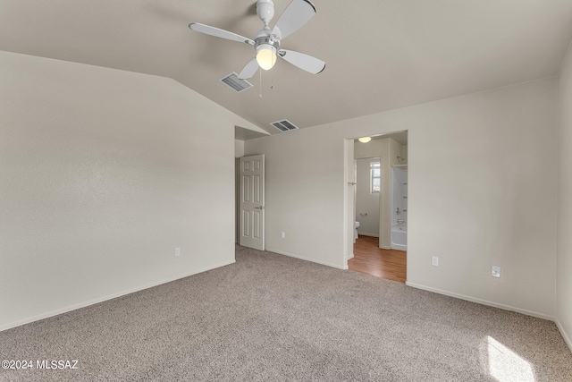 unfurnished bedroom with ceiling fan, vaulted ceiling, hardwood / wood-style flooring, and ensuite bath