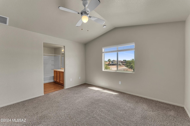 unfurnished bedroom featuring ceiling fan, vaulted ceiling, ensuite bath, and dark wood-type flooring