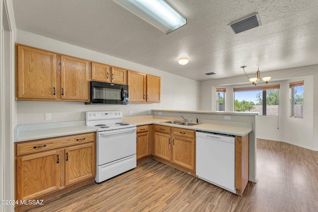 kitchen with kitchen peninsula, light hardwood / wood-style flooring, white appliances, and a chandelier