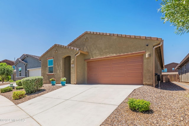 mediterranean / spanish-style home with a garage, concrete driveway, a tile roof, and stucco siding