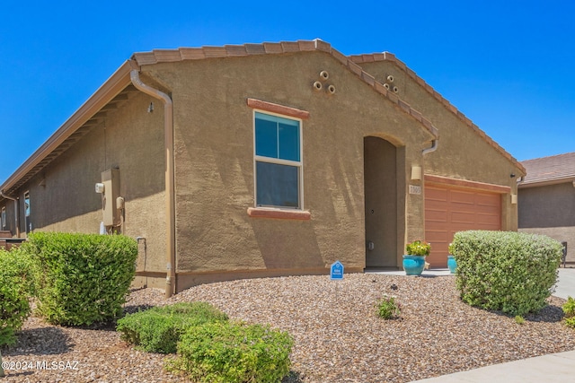 pueblo-style home featuring an attached garage and stucco siding