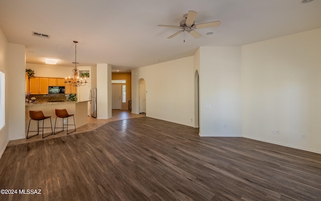 living room with ceiling fan with notable chandelier and dark hardwood / wood-style floors