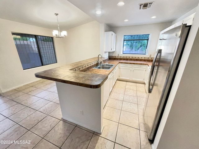 kitchen with kitchen peninsula, stainless steel fridge, light tile patterned floors, and sink