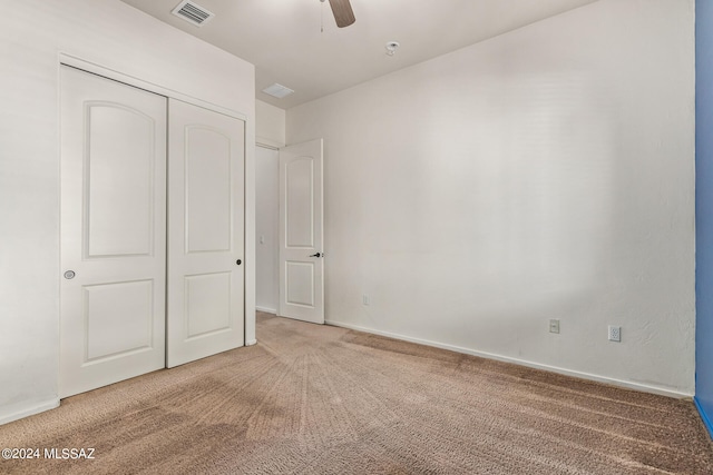 unfurnished bedroom featuring ceiling fan, light colored carpet, and a closet