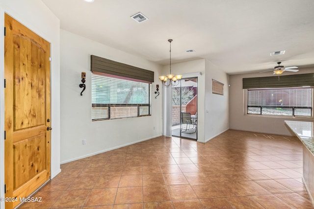 tiled spare room featuring ceiling fan with notable chandelier