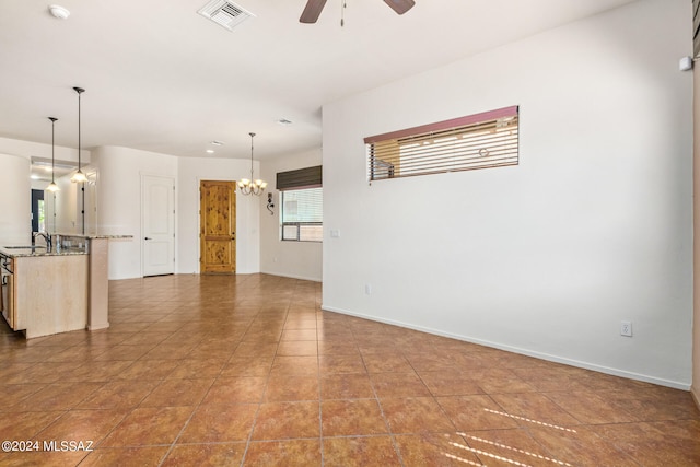 unfurnished living room featuring sink, tile patterned flooring, and ceiling fan with notable chandelier