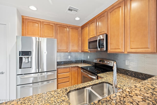 kitchen with stainless steel appliances, backsplash, stone countertops, and sink