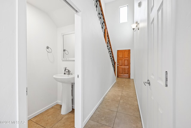 hallway featuring vaulted ceiling, sink, and light tile patterned floors