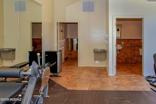 workout room featuring tile walls and light tile patterned floors