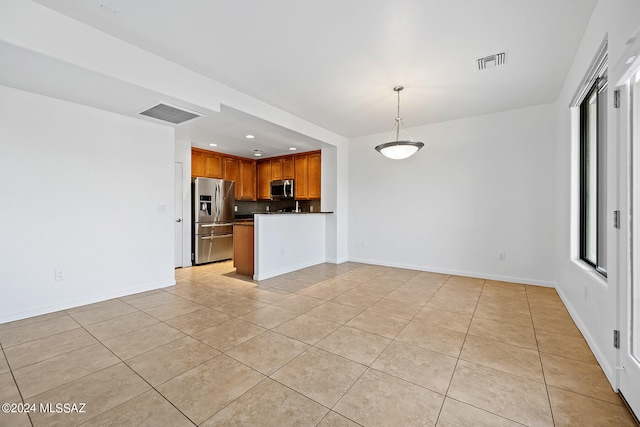 kitchen featuring appliances with stainless steel finishes, light tile patterned floors, decorative backsplash, and pendant lighting