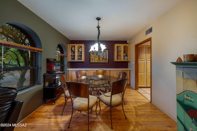 dining space with light hardwood / wood-style floors and a notable chandelier