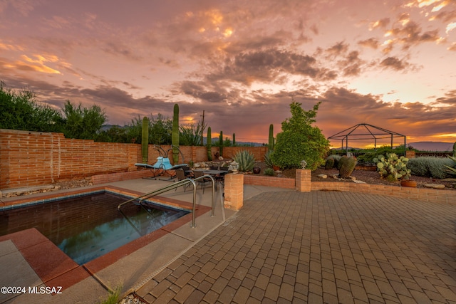 pool at dusk featuring a patio and a gazebo