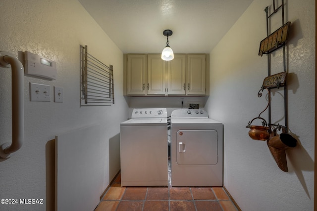 laundry area featuring cabinets, dark tile patterned floors, and washing machine and dryer