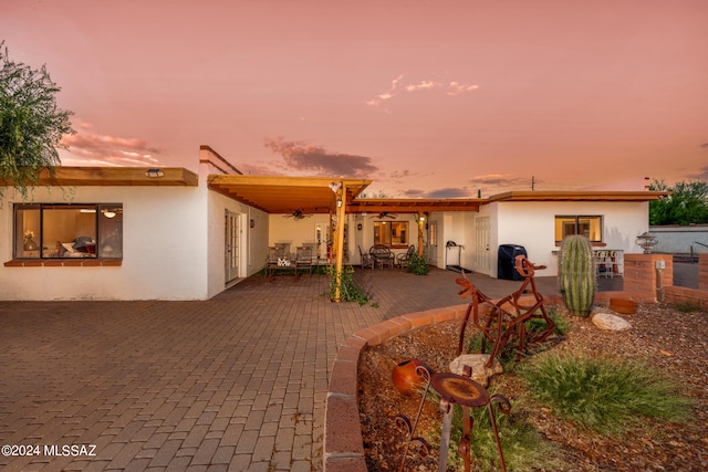 back house at dusk featuring a patio