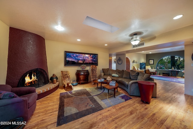 living room featuring ceiling fan, hardwood / wood-style floors, and a large fireplace