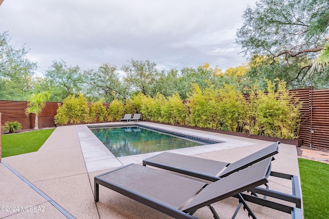 outdoor pool with a fenced backyard and a patio