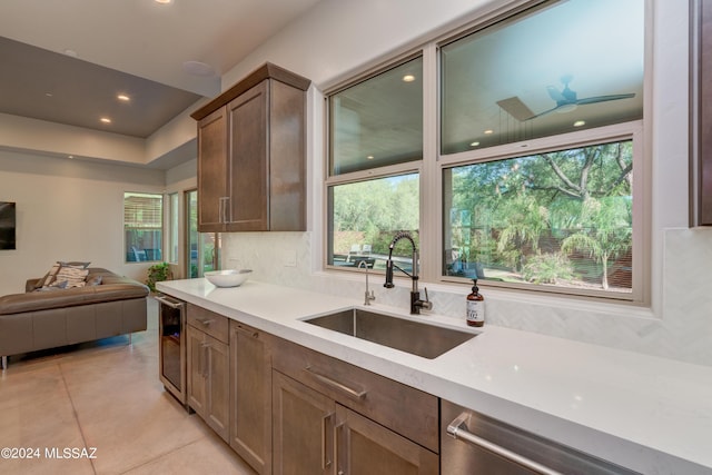 kitchen with wine cooler, light countertops, open floor plan, a sink, and dishwasher