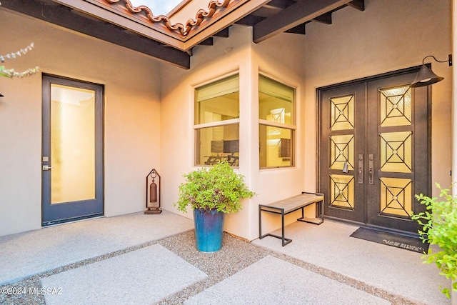 doorway to property with a tile roof and stucco siding