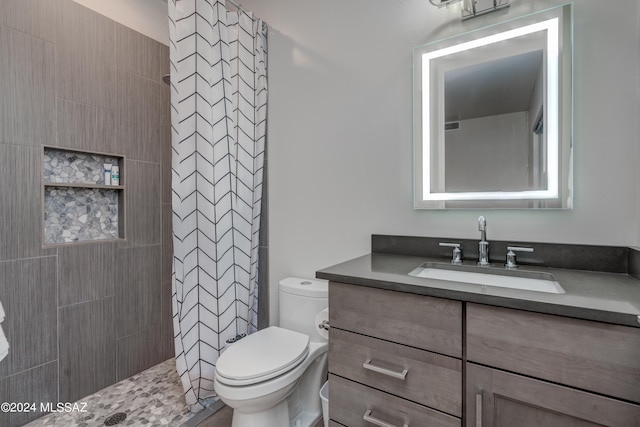 bathroom with vanity, toilet, and a tile shower