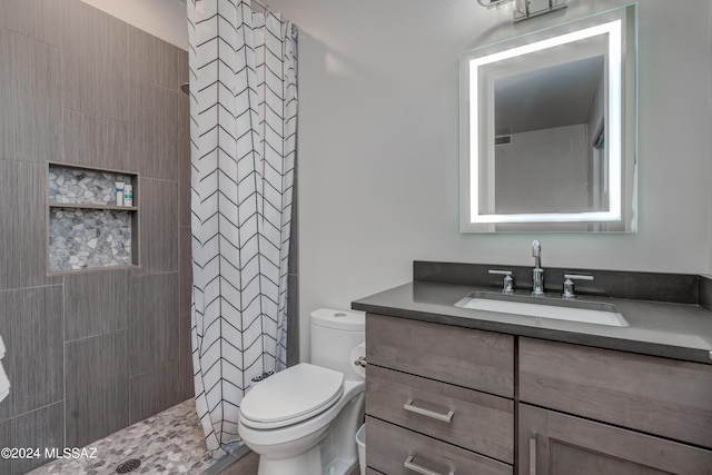 full bath featuring vanity, a tile shower, and toilet