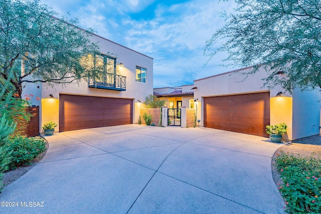 view of front of home featuring a garage, a gate, a balcony, and stucco siding