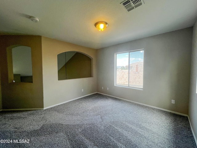 carpeted spare room with visible vents and baseboards