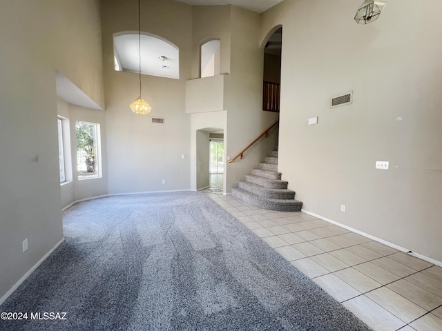 interior space with a towering ceiling, stairway, visible vents, and tile patterned floors