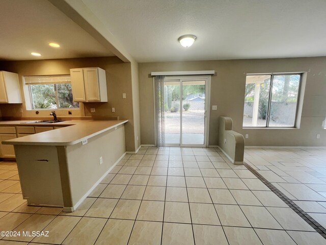 kitchen featuring white cabinetry, kitchen peninsula, light tile patterned floors, and plenty of natural light