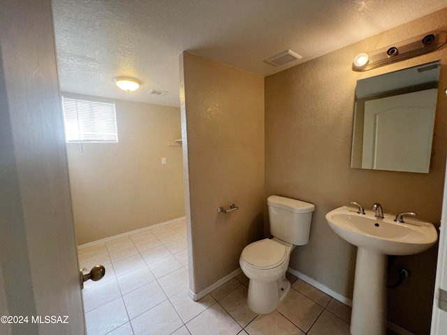 bathroom featuring toilet, a textured ceiling, and tile patterned flooring