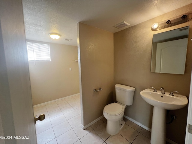 bathroom with baseboards, visible vents, toilet, tile patterned floors, and a textured ceiling