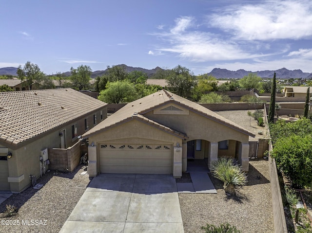 ranch-style home with an attached garage, a mountain view, stucco siding, and driveway