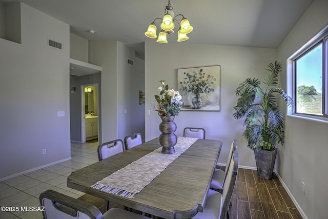 dining room with visible vents, baseboards, a notable chandelier, and vaulted ceiling
