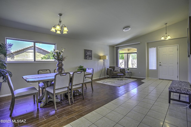 dining area with a chandelier, baseboards, vaulted ceiling, and wood finished floors