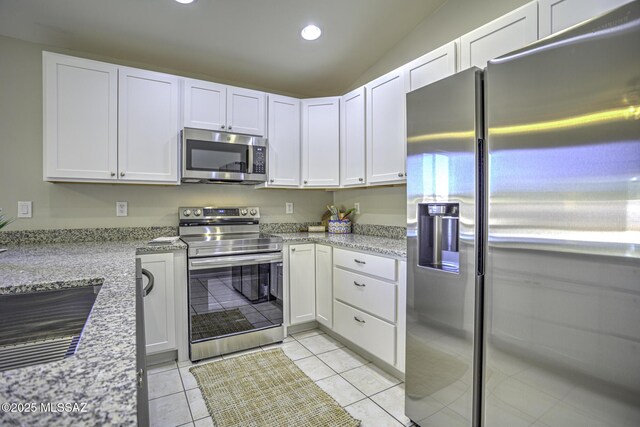kitchen with appliances with stainless steel finishes, light tile patterned flooring, white cabinets, and recessed lighting