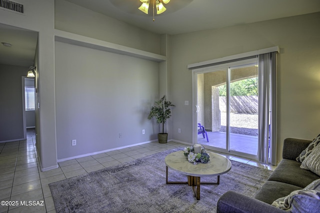 living area featuring tile patterned floors, visible vents, baseboards, and a ceiling fan