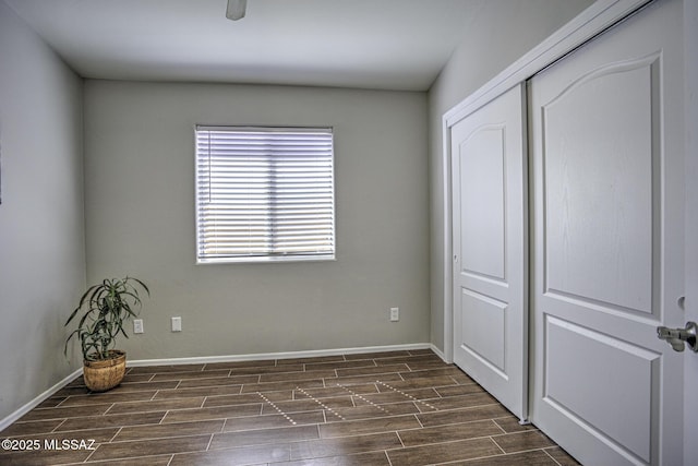 unfurnished bedroom featuring a closet, baseboards, and wood tiled floor
