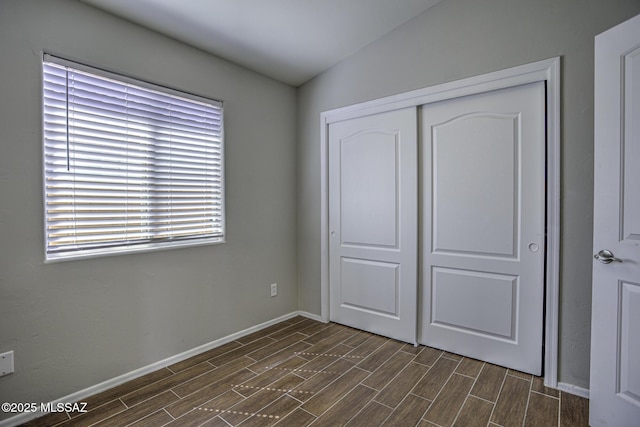 unfurnished bedroom featuring a closet, baseboards, and wood tiled floor