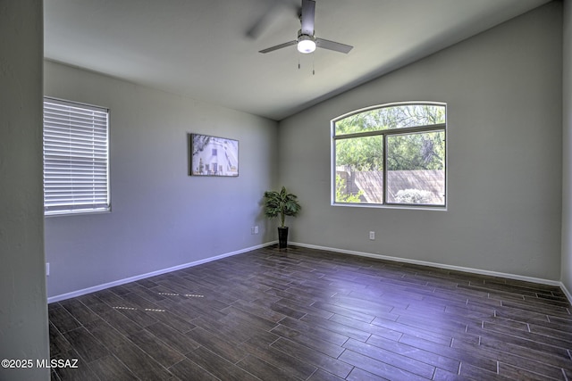 spare room featuring baseboards, a ceiling fan, vaulted ceiling, and dark wood-style floors