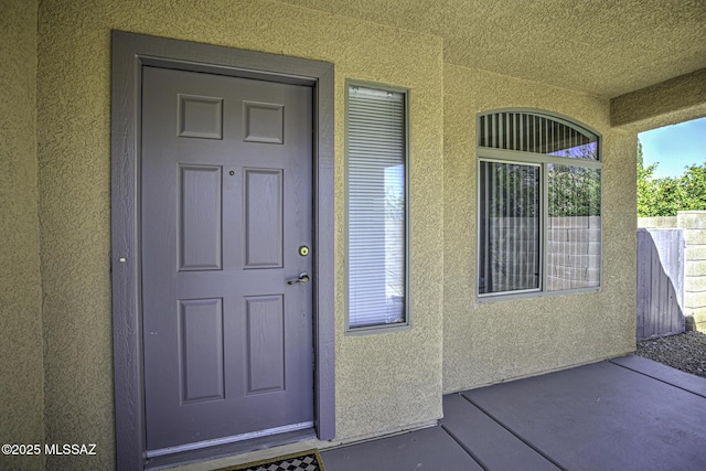 entrance to property with stucco siding and fence
